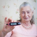 Medicine, age, diabetes, health care and people concept - senior woman with glucometer checking blood sugar level at Royalty Free Stock Photo