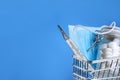 Blue shopping cart with thermometer, medical mask, jar of pills on a blue background. Covid-19 Royalty Free Stock Photo