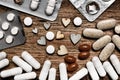 Medicine capsules, many diferent pills spilled on wooden board. Nutritional supplements, minerals, drugs and wooden hearts between Royalty Free Stock Photo