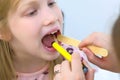 Pediatrician woman looking child girl sore throat using spatula and lantern.