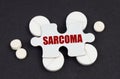 On a black background pills and a puzzle with the inscription - SARCOMA Royalty Free Stock Photo