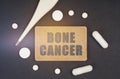 On a black background, a thermometer, pills and a plate with the inscription - BONE CANCER