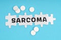 On a blue background pills and puzzles with the inscription - SARCOMA Royalty Free Stock Photo