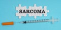 On a blue background, a syringe and puzzles with the inscription - SARCOMA Royalty Free Stock Photo