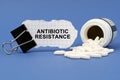 On the blue surface lies a jar of pills and a clip with paper on which is written - ANTIBIOTIC RESISTANCE Royalty Free Stock Photo