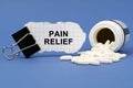 On the blue surface lies a jar of pills and a clip with paper on which is written - PAIN RELIEF Royalty Free Stock Photo