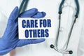 The doctor holds a business card that says - CARE FOR OTHERS