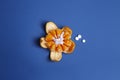 Medicine concept with fresh mandarin and tablets in it. Genetically modified fruit on classic blue background