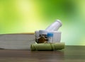 Medicine concept - homeopathic pills medicine bottles with a book, rolled leaf and mortar on brown surface with green leaf Royalty Free Stock Photo