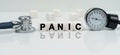 On a reflective white surface lies a stethoscope and cubes with the inscription - PANIC