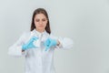 Pretty young intern girl holding white bottle of pills, giving thumb down, showing her disapproval. Royalty Free Stock Photo