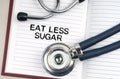 On the table is a stethoscope, a pen and a notebook in which it is written - Eat Less Sugar Royalty Free Stock Photo