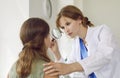 Professional dermatologist examines face of teenage girl with magnifying glass in her office.