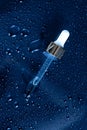 Medicine dropper on dark blue background with water drops and splashes Royalty Free Stock Photo