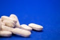 Many white medicine tablets on blue background. White pills, concept Ã¢â¬â pharmacy. Medicines drugs. Royalty Free Stock Photo