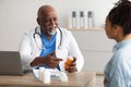 Experienced black doctor showing pills to female patient Royalty Free Stock Photo