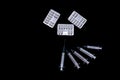 white pills in silver packs and medical syringes on a black background, isolate, copy space Royalty Free Stock Photo