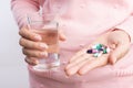 Medicine, health care and people concept - close up of woman taking in pill and another hand holding a glass of clean mineral Royalty Free Stock Photo