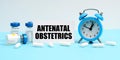 An alarm clock, pills, injections and a card with the inscription - Antenatal Obstetrics