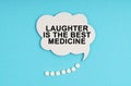 On a blue table are pills and a white plate with the inscription - Laughter is the Best Medicine