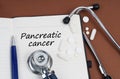 On a brown surface lie pills, a pen, a stethoscope and a notebook with the inscription - Pancreatic cancer