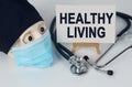 Skull in mask and cap, stethoscope and easel with canvas on which it is written - HEALTHY LIVING