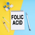 A syringe, ampoules and a notebook with the inscription - folic acid
