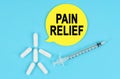 Syringe, human figure made of pills and paper sticker with the inscription - PAIN RELIEF Royalty Free Stock Photo