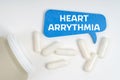 On the table are pills and a blue sign that says - Heart arrythmia