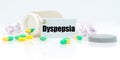 On a white reflective background, there are pills and a jar of drugs with a tag that says - Dyspepsia