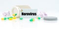 On a white reflective background, there are pills and a jar of drugs with a tag that says - Norovirus