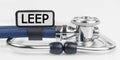 On the white surface lies a stethoscope with a plate with the inscription - LEEP Royalty Free Stock Photo