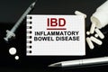 On the black surface are pills, a syringe and a notebook with the inscription - IBD-Inflammatory Bowel Disease Royalty Free Stock Photo