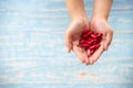 Medicine, healthcare, concept. Closed up hands hold the red medicines or vitamines on the wooden background