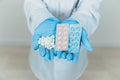 Many small white pill and two blisterpacks of blue and pink pills in the doctor`s hands dressed in the medical Royalty Free Stock Photo
