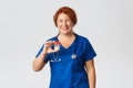 Medicine, healthcare and coronavirus concept. Cheerful smiling female meical worker, doctor in scrubs showing container