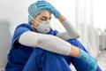 Sad doctor or nurse in face mask holding to head Royalty Free Stock Photo