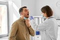 doctor checking male patient's throat at hospital