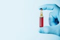 Medicine, injections, vaccination concept. Hands in medical gloves holding ampoule with vitamin B on blue background. Copy space. Royalty Free Stock Photo