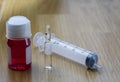medicinal syrup, glass ampoule with medicine and disposable syringe on wooden base