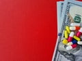 Medicine money pills on dollar bills on red background