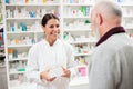 Happy female pharmacist giving medications to senior male customer Royalty Free Stock Photo