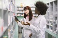 Medicine, pharmaceutics, health care and people concept. Two young multiethnic female pharmacist, African and Caucasian Royalty Free Stock Photo