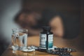 Medicine, pills, glass of water. Person having flu, fever and headache on sofa couch. Caught cold in winter, Sick man sleeping in Royalty Free Stock Photo