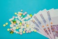 Medicine pills over euro banknotes on a blue background. Covid-19 coronavirus pills are on the euro banknote. The Royalty Free Stock Photo