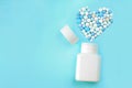 Medicine pills, tablets and capsules for the treatment of heart disease. Heart shape and bottle of pills. Blue background. Copy sp Royalty Free Stock Photo