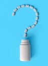 Medicine plastic container and spilled pills arranged in shape of question mark on blue background