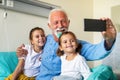 Happy grandchildren visiting grandfather at hospital ward. Support, family and healthcare concept. Royalty Free Stock Photo