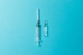 Medicine syringe and ampoule on blue background. Concept of different treatment methods. Minimalistic