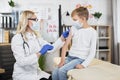 Caucasian boy getting injection by female doctor at hospital